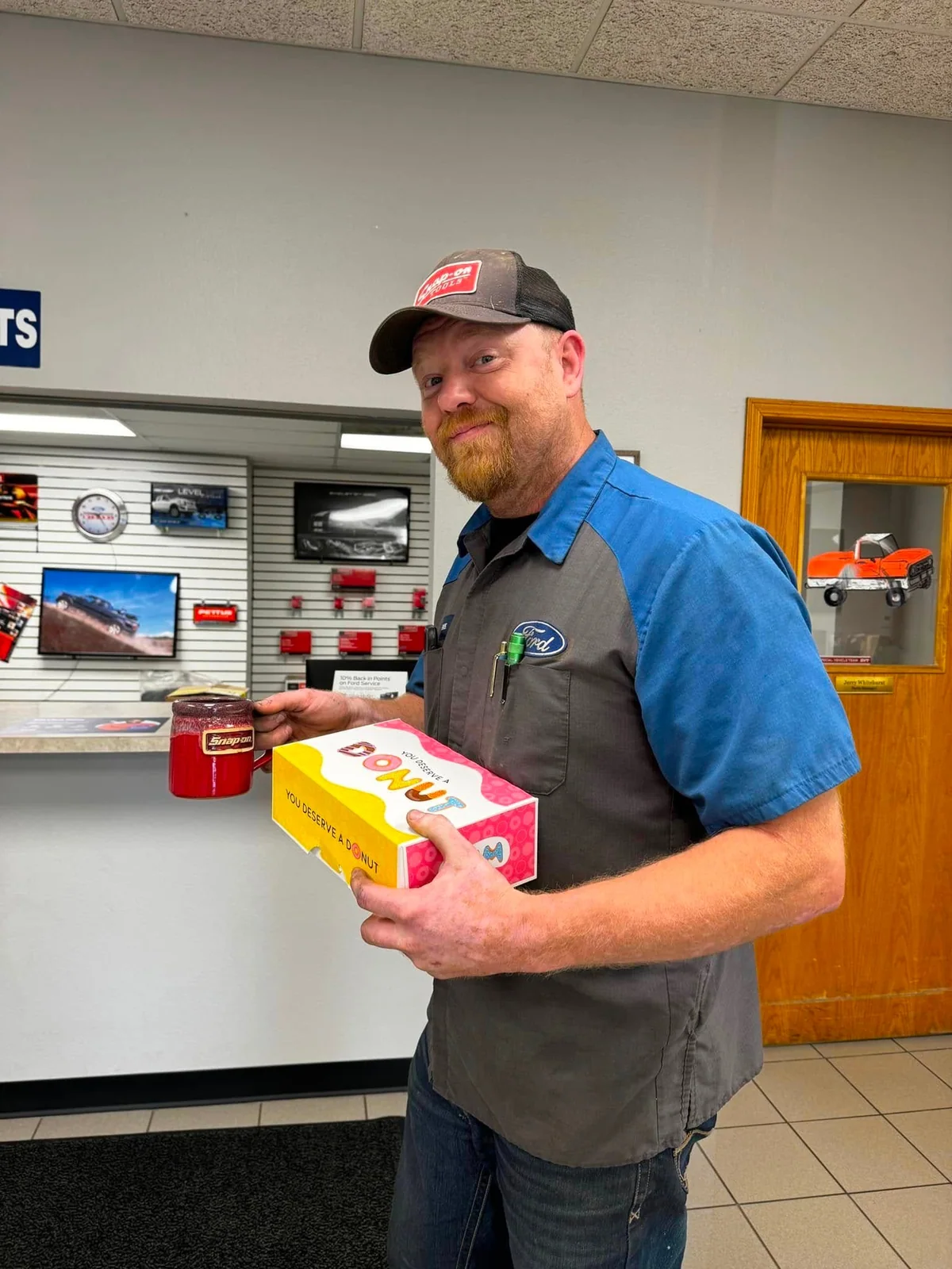 Pettus Ford technician holding a box of donuts