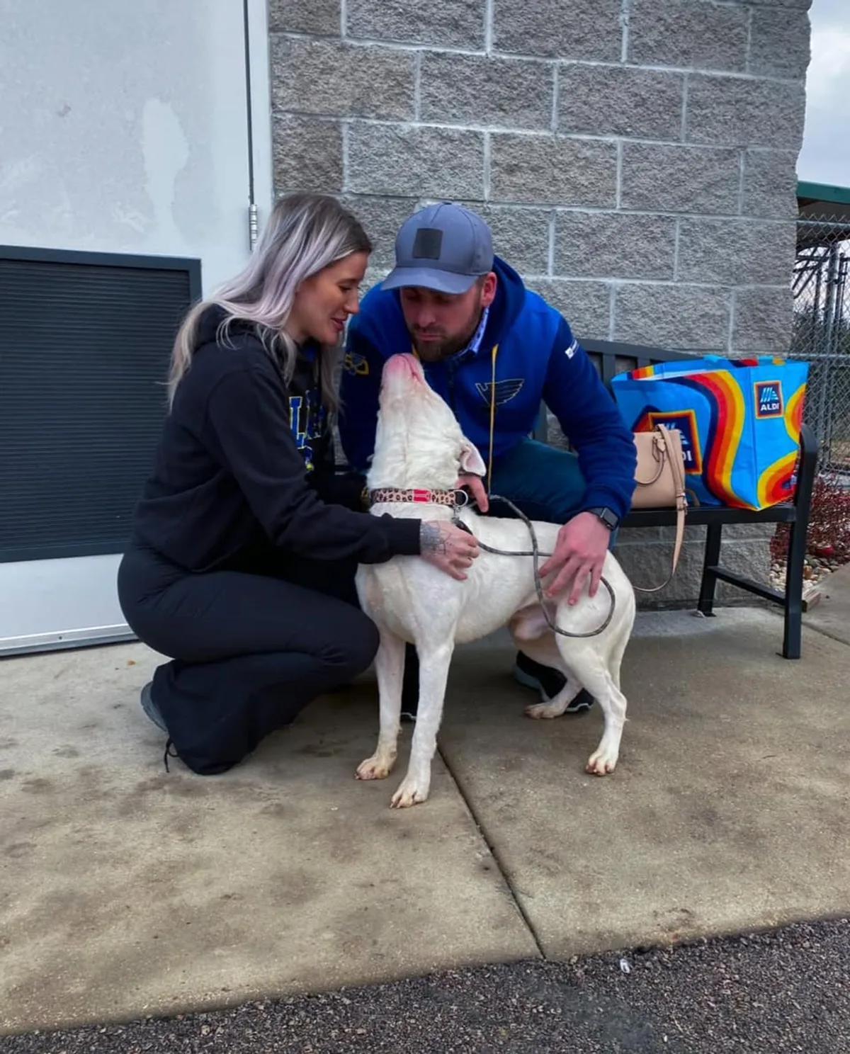 Two supporters spending time with an adoptable white dog